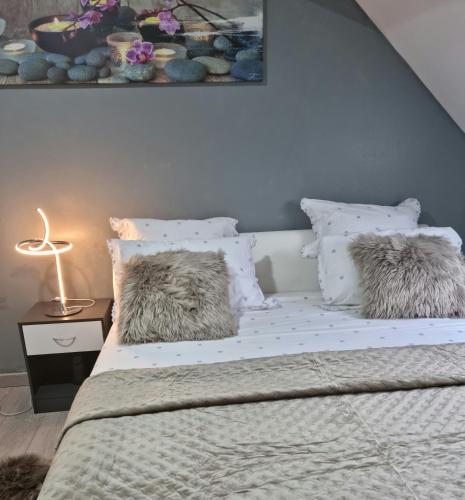 une chambre avec un lit avec des draps blancs et des oreillers dans l'établissement magnifiqueT3 hyper centre beauvais design confort, à Beauvais