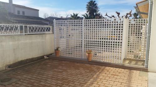 une clôture blanche avec des plantes en pot sur une terrasse dans l'établissement Studette Roseaux, à Balaruc-le-Vieux