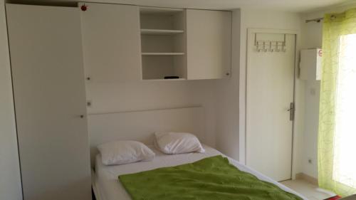 une chambre avec un lit avec une couverture verte dessus dans l'établissement Studette Roseaux, à Balaruc-le-Vieux