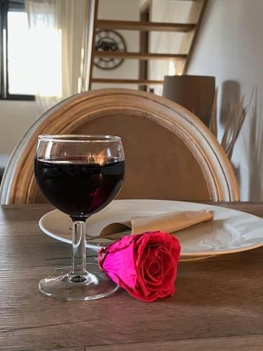 un verre de vin et une rose rouge sur une table dans l'établissement Joli duplex proche du lac Léman, à Messery