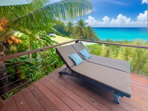 a bench on a deck with a view of the ocean at Vue Mer/3Beds/Piscine/wifi/900 mètres de la plage in Deshaies