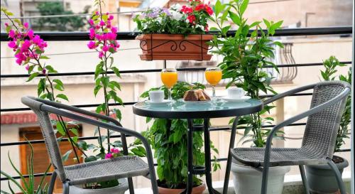 a table and chairs on a balcony with flowers at Luxury Apartment near Acropolis in the Heart of Athens in Athens