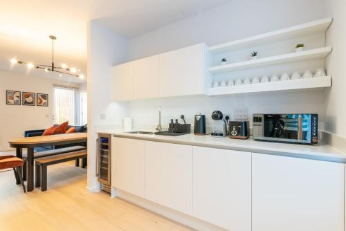 a kitchen with white cabinets and a wooden table at Modern 5 Bedroom Town House with off St Parking in Bristol