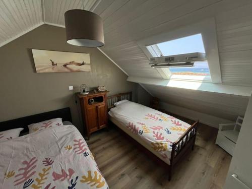 - une chambre mansardée avec 2 lits et une fenêtre dans l'établissement Les pieds dans l'eau - Cosqueville Vicq-mer, à Cosqueville