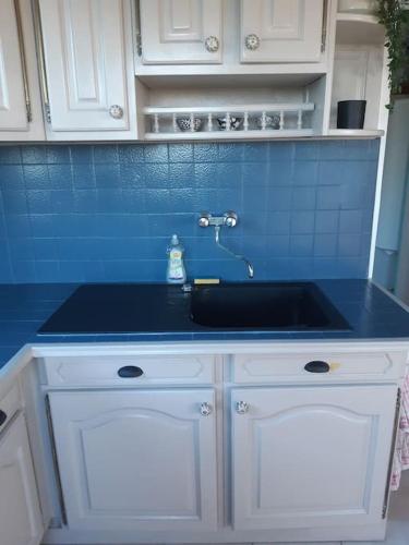 - un comptoir de cuisine avec évier et carrelage bleu dans l'établissement Les pieds dans l'eau - Cosqueville Vicq-mer, à Cosqueville