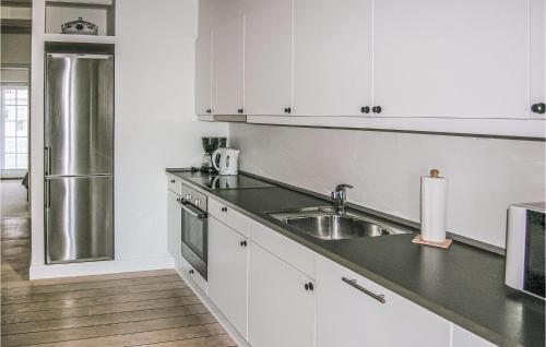a kitchen with white cabinets and a stainless steel refrigerator at Apartment Færgevej X in Bagenkop