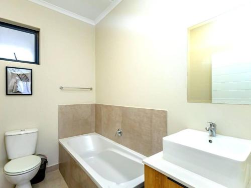 a bathroom with a white tub and a toilet and a sink at Urban Retreat in Midrand
