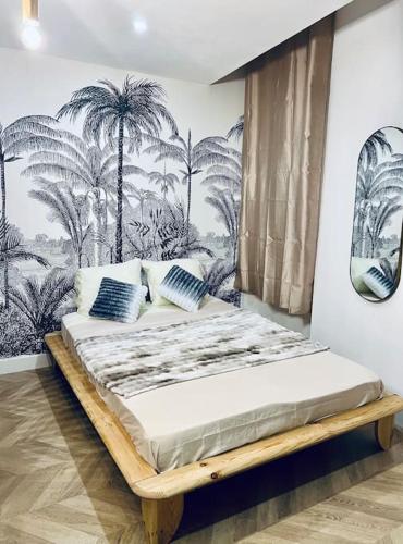 Ce lit se trouve dans un dortoir orné d'une fresque murale de palmiers. dans l'établissement Nid cosy au cœur de Martigues, à Martigues