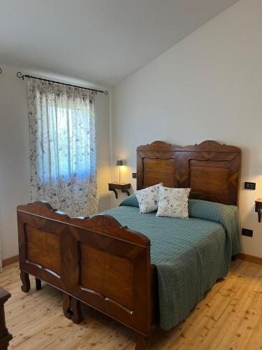 a bedroom with a large wooden bed and a window at Casa vacanze Pierangela in Susegana