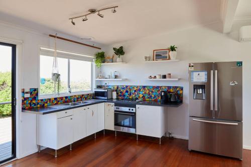 a kitchen with white cabinets and stainless steel appliances at Ocean View Getaway in Port Campbell