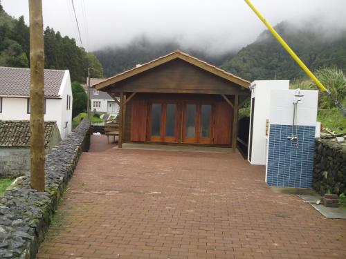 a house with a garage with mountains in the background at Casa dos Manos in Furnas