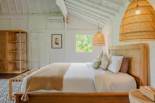a bedroom with a large bed with white sheets and pillows at Villa Umasana Private Balinese House and Garden in Canggu