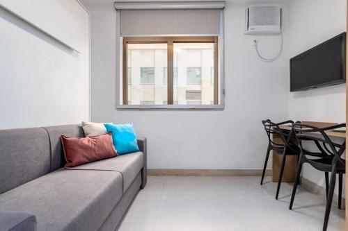 ein Wohnzimmer mit Sofa und Tisch in der Unterkunft Studio Luxo Piscina e Ar Condicionado in Rio de Janeiro