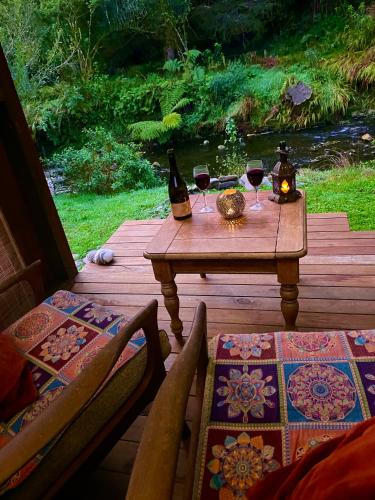 a table with two glasses of wine on a wooden deck at River Song Retreat Golden Bay in Onekaka