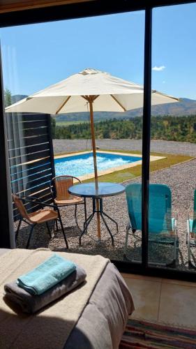 a patio with an umbrella and a table and chairs at Grado8punto8 Glamping Valle de Los Artistas in Lolol