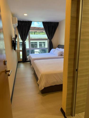 Un dormitorio con dos camas y una ventana. en T Lodge, Kapit, en Kapit