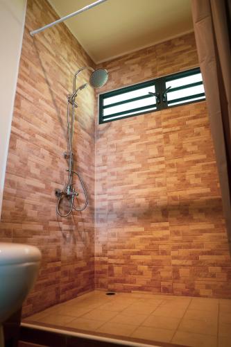 a shower in a bathroom with a brick wall at Teahupo'o Wave Lodge in Teahupoo