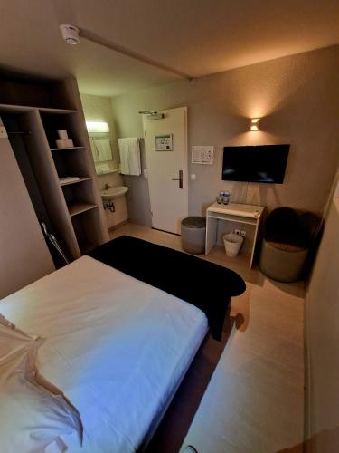 a small bedroom with a bed and a television at Hotel Bristol in Luxembourg