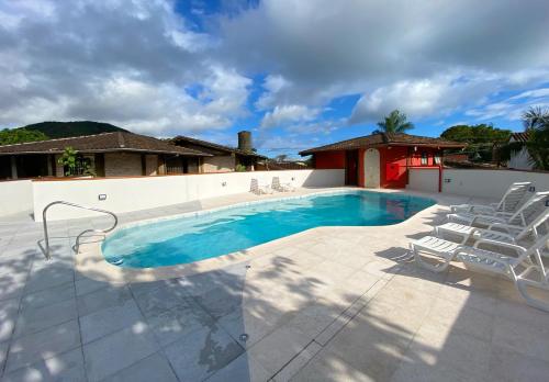 a swimming pool with chairs and a house at Patio Camburi - Flat com Piscina à 60m da Praia de Camburi in São Sebastião