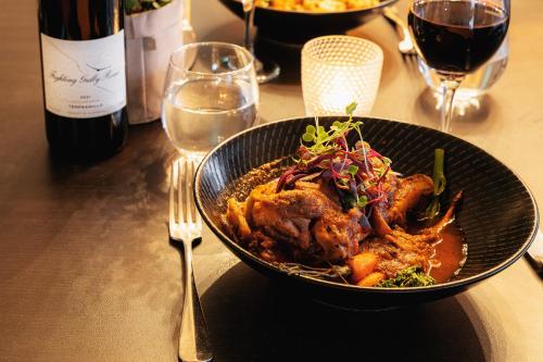 a bowl of food on a table with a bottle of wine at Mercure Albury in Albury