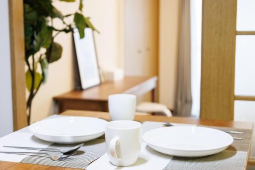 a table with two white plates and cups on it at Shippo Town Hotel Nishiohashi-eki in Osaka