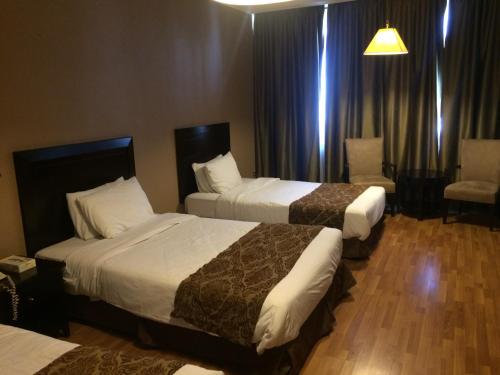 a hotel room with two beds and a chair at Shepherd Hotel in Amman