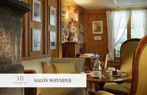 a living room with a fireplace and a table at Monte Rosa Boutique Hotel in Zermatt