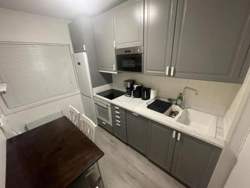 a kitchen with gray cabinets and a sink and a table at Central 2 bedroom apartment in Lillehammer