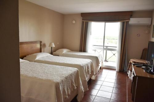 a hotel room with three beds and a window at Los Naranjos Termal in Termas del Daymán