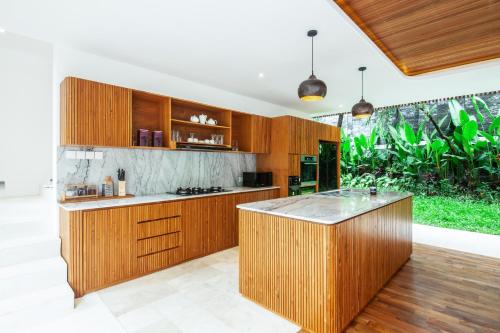 an open kitchen with wooden cabinets and a large island at Seminyak Villa Paya paya Luxury near beach-Potato Head in Seminyak