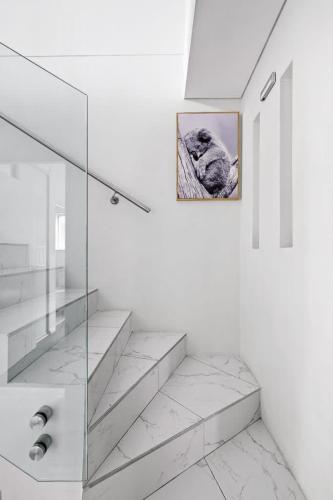a white bathroom with stairs and a picture on the wall at Modern Queen Room - Private Spot at Revesby - Shared Bathroom in Revesby