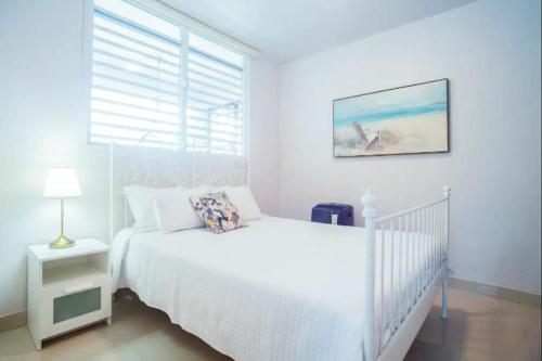 a white bedroom with a white bed and a window at 103-Delightful GEM in the city, Close to the Beach with Free Parking in San Juan