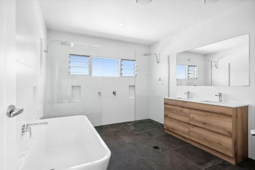 a bathroom with a tub and a toilet and a sink at Beautiful Three-Story Villa footsteps to the Beach in Coolum Beach