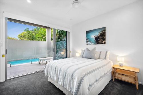 a white bedroom with a bed and a large window at Beautiful Three-Story Villa footsteps to the Beach in Coolum Beach