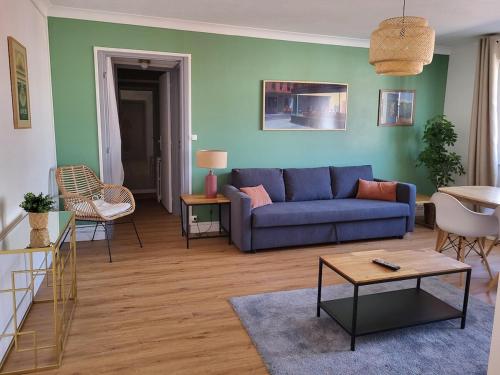 un salon avec un canapé bleu et des chaises dans l'établissement Appart Cosy parking privé Croisé Laroche près tram, à Marcq-en-Barœul