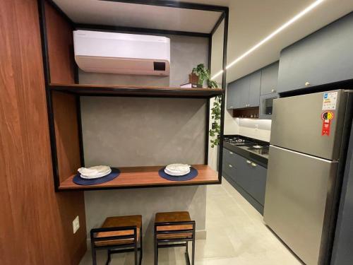 a kitchen with a counter with two chairs and a refrigerator at Varanda do Mar - Flat Intermares in Cabedelo