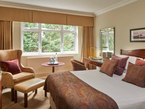 ein Hotelzimmer mit einem Bett und einem Stuhl in der Unterkunft Macdonald Berystede Hotel & Spa in Ascot