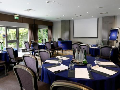 a conference room with blue tables and chairs and a screen at Macdonald Berystede Hotel & Spa in Ascot