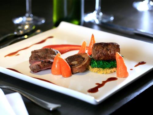 a plate of food with meat and carrots on a table at Macdonald Berystede Hotel & Spa in Ascot