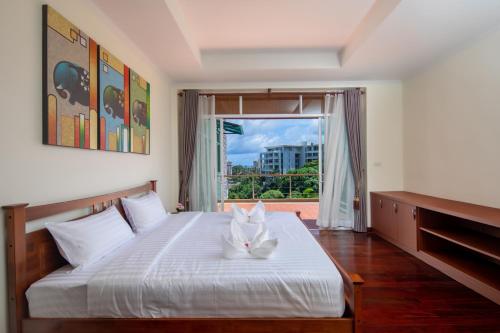 a bedroom with a large white bed with a window at Prima Villas Karon Phuket in Karon Beach