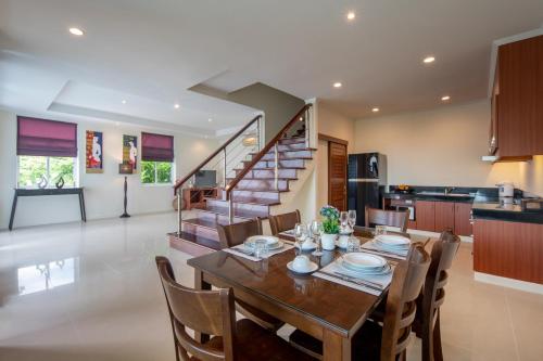 a dining room with a table and chairs and a staircase at Prima Villas Karon Phuket in Karon Beach
