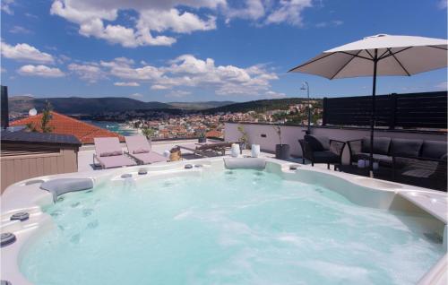 a hot tub on a roof with chairs and an umbrella at Gorgeous Apartment In Okrug Gornji in Trogir