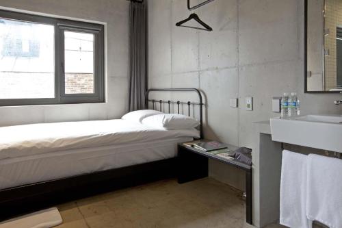 a small bedroom with a bed and a sink at Playce Camp Jeju in Seogwipo