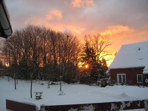 a house in the snow with the sunset in the background at Ferienwohnung Schneemann in Hohegeiß