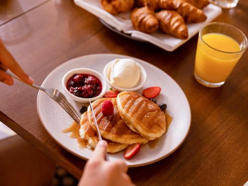 a person eating a plate of waffles and fruit on a table at Novotel Sydney Parramatta in Sydney