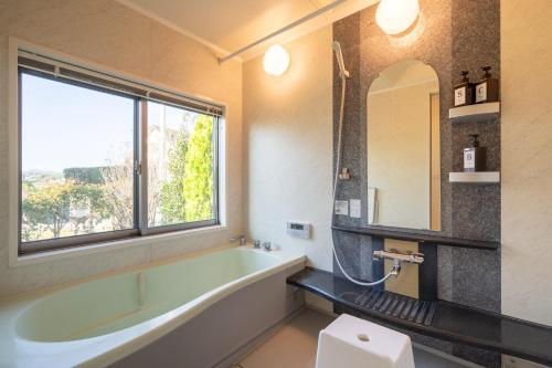 a bathroom with a large tub and a window at S-villa Minamiboso rosemar in Awa