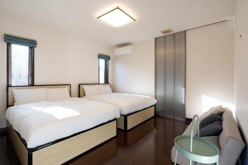 a bedroom with two beds and a couch in it at S-villa Minamiboso rosemar in Awa