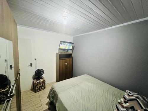 a bedroom with a bed and a flat screen tv at Casa na Praia Azul in Passo de Torres