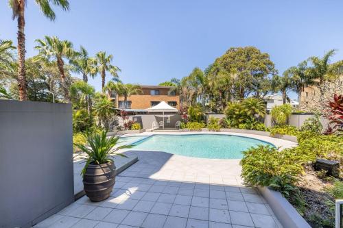 a swimming pool in a yard with palm trees at Florentine 14 - 11 Columbia Close Aircon Wifi unsurpassed water views in Nelson Bay