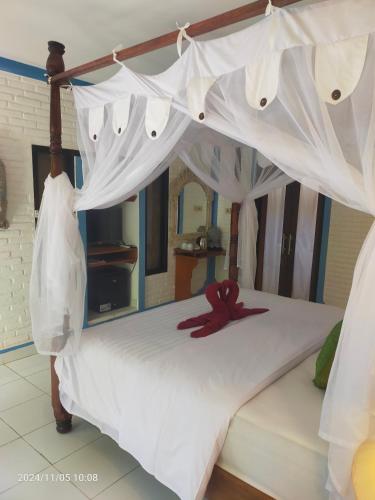 a bed with a red ribbon on top of it at Puri Oka Beach Bungalows in Candidasa